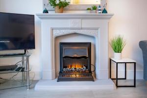 ein Kamin in einem Wohnzimmer mit Fernseher in der Unterkunft Rose Cottage in Sidmouth