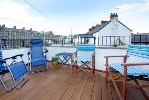 eine Terrasse mit 3 Stühlen, einem Tisch und Stühlen in der Unterkunft Rose Cottage in Sidmouth