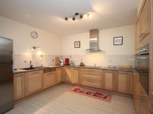 eine Küche mit Holzschränken und einem Edelstahlkühlschrank in der Unterkunft Grand T3 au Mont-Dore avec Terrasse, Parking et WiFi, à 200m du Centre - FR-1-608-177 in Le Mont-Dore