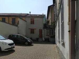 due auto parcheggiate in un vicolo accanto agli edifici di Casa di Simone a Como