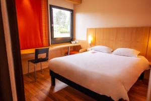 - une chambre avec un grand lit blanc et une fenêtre dans l'établissement Hôtel ibis Guingamp Cœur de Bretagne, à Ploumagoar