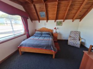 um quarto com uma cama e uma cadeira em Hospedaje JUALIC em Valdivia