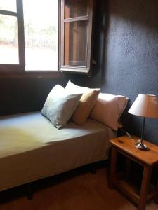 1 dormitorio con cama con almohadas y ventana en Casa rural en el campo LAS DALIAS, en Tordera