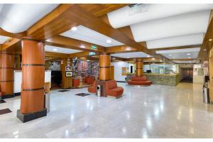 a lobby with wooden columns and red chairs in a building at Hotel Palace México in Mexico City