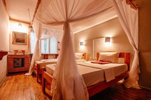 two beds in a room with a canopy bed at Miseni Retreat in Saadani