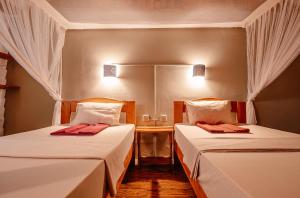 Duas camas num pequeno quarto com uma mesa em Miseni Retreat em Saadani