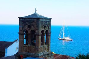 a boat in the water next to a tower with a boat at Κyma Mansion in Monemvasia in Monemvasia
