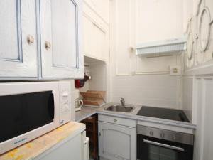 a kitchen with white cabinets and a sink and a microwave at Appartement Mont-Dore, 2 pièces, 4 personnes - FR-1-608-108 in Le Mont-Dore