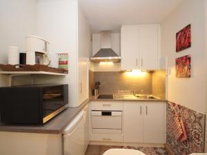 a small kitchen with white cabinets and a sink at Appartement Mont-Dore, 2 pièces, 4 personnes - FR-1-608-114 in Le Mont-Dore