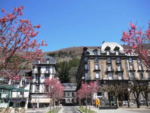 a large building on a city street with pink trees at Appartement Mont-Dore, 2 pièces, 4 personnes - FR-1-608-114 in Le Mont-Dore