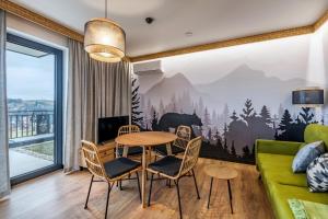 a living room with a table and chairs and a couch at Widokowe Apartamenty na Kępiatym Wzgórzu & Wellness in Czarna Góra