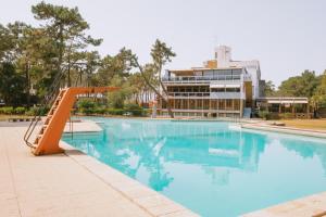an empty swimming pool with a slide in front of a building at Parque do Rio Ofir Hotel in Esposende