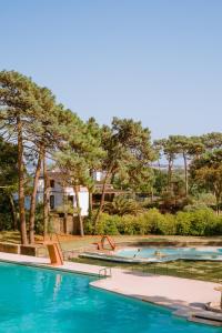 una piscina con 2 piscinas con árboles en el fondo en Parque do Rio Ofir Hotel, en Esposende