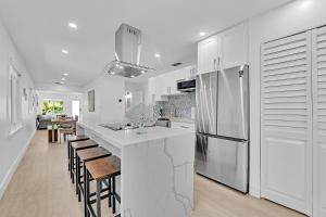 a kitchen with white cabinets and a bar with stools at Quiet and secluded 4 bedroom home! in Fort Lauderdale