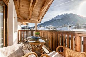 a balcony with a table and chairs and a mountain at Casa Flora in Dobbiaco