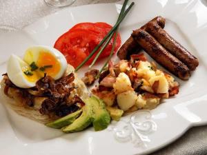 a plate of food with eggs sausage and tomatoes at Fisher House Victoria Bed and Breakfast in Victoria