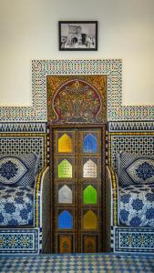 a bedroom with a wooden door with colorful tiles at Riad Green House in Fès