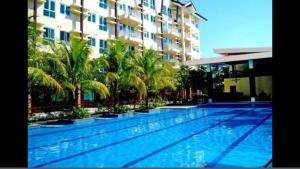 a large swimming pool with palm trees in front of a building at Rochester Condo in Manila +7 photos