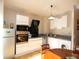 eine Küche mit weißen Geräten und einem Esstisch in der Unterkunft Bel appartement T3 avec WiFi et parking, Mont-Dore - FR-1-608-13 in Le Mont-Dore + 8 Fotos