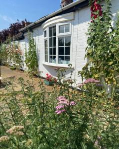 a house with a garden with flowers in front of it at Field Cottage in Whittlesey