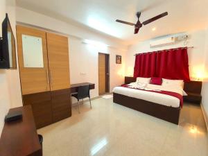 班加羅爾的住宿－Sai Shreyas Residency, Best Hotel near Bangalore Airport，一间卧室配有一张带红色窗帘的床和一张书桌