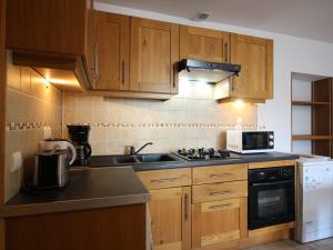a kitchen with wooden cabinets and a stove top oven at Appartement T3 avec Parking à La Bourboule, à 500m des Thermes et du Centre, WiFi Inclus - FR-1-608-14 in La Bourboule