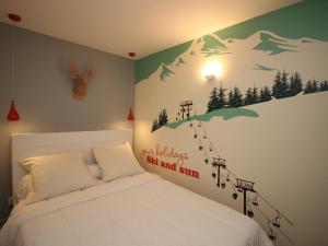 ein Schlafzimmer mit einem weißen Bett und einem Wandbild aus den Bergen in der Unterkunft Appartement T3 avec Jardin Privatif et WIFI à Mont-Dore, Rénové, Parking et Garage Inclus - FR-1-608-37 in Le Mont-Dore