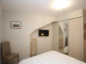 um quarto com uma cama branca e uma cadeira em Appartement Mont-Dore, 3 pièces, 6 personnes - FR-1-608-28 em Le Mont-Dore