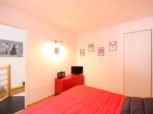 1 dormitorio con cama roja y TV en Appartement Mont-Dore, 2 pièces, 4 personnes - FR-1-608-68, en Le Mont-Dore