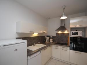 eine weiße Küche mit Spüle und Mikrowelle in der Unterkunft Le Mont-Dore: Beau T2bis avec terrasse, 2 chambres, WiFi - FR-1-608-70 in Le Mont-Dore