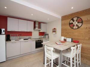 a kitchen with white cabinets and a wooden wall at Mont-Dore : T2 spacieux avec terrasse, 300m des thermes, résidence rénovée, parking privé - FR-1-608-98 in Le Mont-Dore +8 photos
