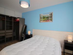 Un dormitorio con una gran cama blanca con una luz azul. en Bel Appartement T3 avec WIFI et Parking, Résidence de Standing, 300m des Thermes au Mont-Dore - FR-1-608-87, en Le Mont-Dore
