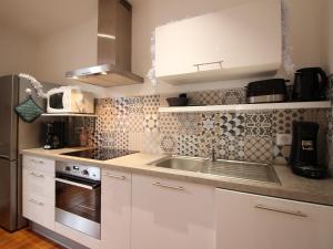 eine weiße Küche mit Spüle und Kühlschrank in der Unterkunft Charmant appartement T3 avec Wifi au centre de La Bourboule, proche Thermes et commerces - FR-1-608-96 in La Bourboule + 8 Fotos