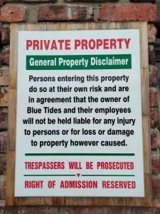 een bord op een bakstenen muur met de woorden privé eigendom beheerd bij Blue Tides in Port Elizabeth