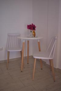 a white table with two chairs and a vase of flowers on it at Louros rooms in Koufonisia