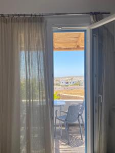 a sliding glass door to a patio with a table and chairs at Louros rooms in Koufonisia