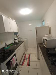 eine Küche mit einer Mikrowelle und einem Kühlschrank in der Unterkunft Village Hospedagens in Natal