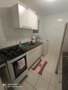 a kitchen with white cabinets and a stove top oven at Village Hospedagens in Natal