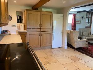 a kitchen with a white refrigerator and a living room at Scenic Welsh Cottage in the Brecon Beacons in Crickhowell