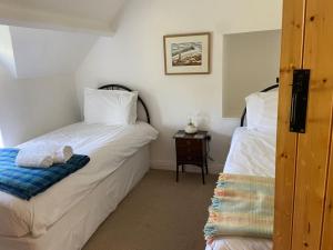 a bedroom with two beds and a table with a night stand at Scenic Welsh Cottage in the Brecon Beacons in Crickhowell