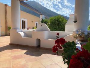 a patio with a white bench and red flowers at Casa Il Girasole, panoramica e a pochi passi dal centro di Malfa in Malfa
