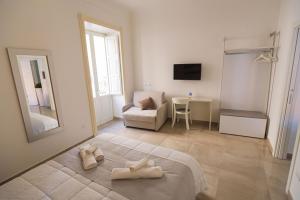 a white bedroom with two towels on a bed at Panorama Alfeo in Siracusa