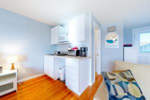 una pequeña cocina con armarios blancos y un sofá en Little Gem at Hampton Beach, en Hampton
