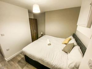 a bedroom with a bed with white sheets and gold pillows at Liverpool City Centre Studio Apartment in Liverpool