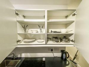 a kitchen with white cabinets with plates and utensils at Liverpool City Centre Studio Apartment in Liverpool