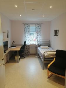 a bedroom with a bed and a desk and a computer at Vallabiten Rum och Lägenheter in Växjö