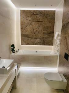 a bathroom with a tub and a toilet and a sink at Jasna SportHotel & SPA in Gliwice