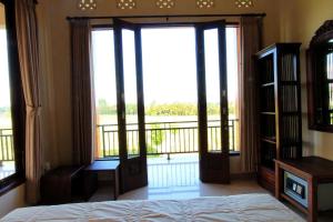1 dormitorio con 1 cama y balcón con ventanas en Ubud Canti Accommodation, en Ubud