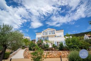 a white house on a hill with a blue sky at Rooms Salvia in Cres
