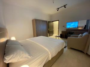 1 dormitorio con 1 cama blanca grande y TV en نايتس للوحدات المفروشة, en Tabuk